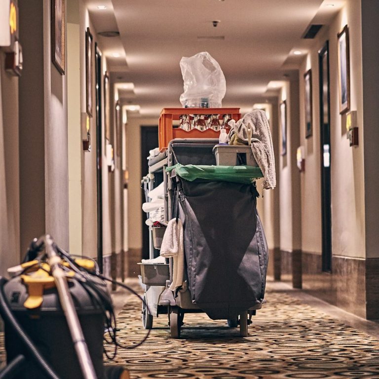 Wagen mit Putzutensilien und Handtüchern in einem Hotelflur.
